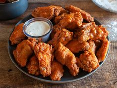 chicken wings on a plate with ranch dressing in the bowl next to it and a red sign that says new