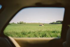 the view from inside a car looking at a green field with a house in it