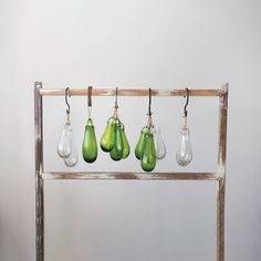 four green vases are hanging from a wooden rack