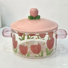 a glass casserole dish with a pink lid and flowers painted on the side