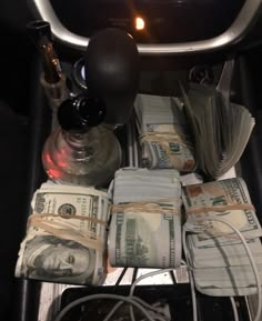 a bunch of money sitting on top of a table next to a bottle and some wires