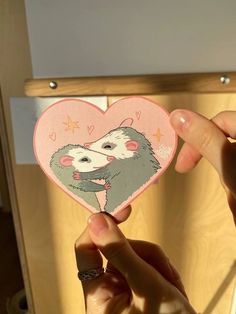 someone holding up a heart shaped card with an animal on it