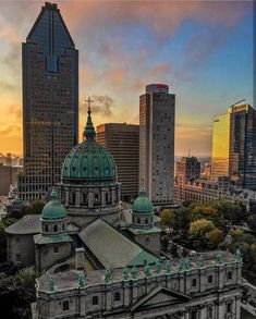 an old building in the middle of a city with tall buildings and green roof tops