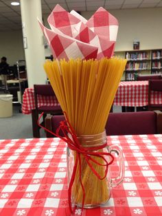 a jar filled with pasta sitting on top of a red and white checkered table cloth