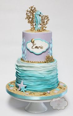 a three tiered cake decorated with blue, purple and gold icing on a stand