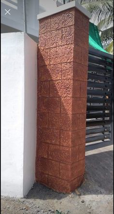 a tall brick pillar sitting next to a white wall near a fence and palm tree