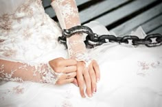 a woman in white dress sitting on a bench with a chain attached to her arm