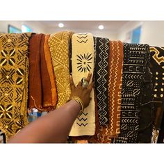 a woman's hand is on top of a rack of different colored scarves