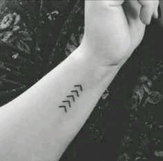 black and white photo of a person's arm with an arrow tattoo on it