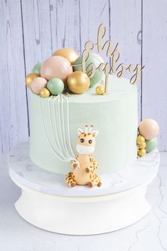 a cake with a giraffe decoration on the top and balloon decorations around it