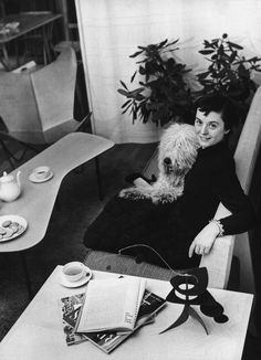 a black and white photo of a woman sitting on a couch with a dog in her lap