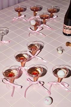 there are many wine glasses on the table with pink ribbons around them, and one is empty