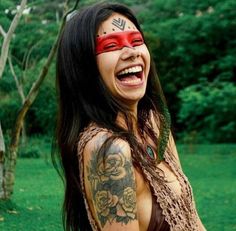 a woman with tattoos on her chest and face painted like a native american warrior smiling