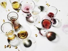 wine glasses filled with different colored wines on top of a white tablecloth covered in confetti