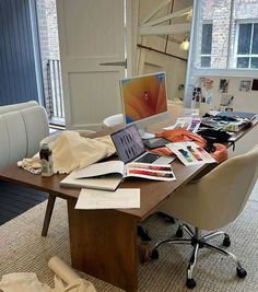 an office desk is cluttered with papers and laptops