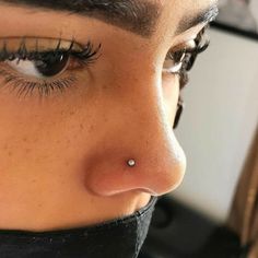 a close up of a woman's nose with long lashes and piercing on it