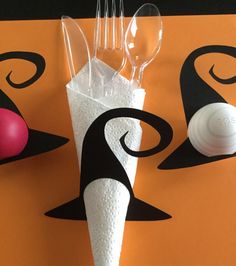 there are plastic utensils and spoons on this orange tablecloth with black swirl designs