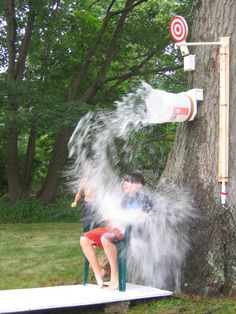 two children are sitting on a bench and playing with water from a sprinkler