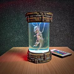 a glass jar with an image of a lizard in it on a table next to a remote control