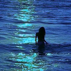 a woman is swimming in the ocean at night