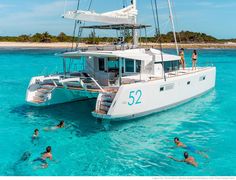 people are swimming in the ocean near a boat that is floating on clear blue water