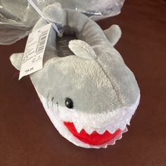 a stuffed shark toy with a tag on it's ear sitting on a table