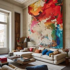 a living room filled with lots of furniture and a large painting on the wall above it