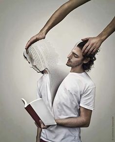 a man is holding an open book while another mans hands hold it over his head