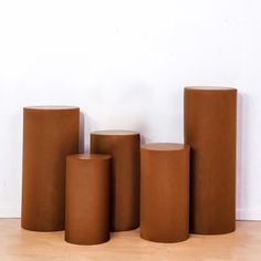 three tall brown vases sitting next to each other on top of a wooden floor