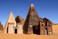 an image of desert setting with pyramids and mud huts in the foreground on a sunny day