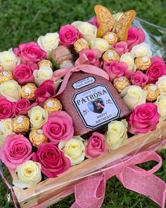 a box filled with lots of pink and white flowers next to a bunch of chocolates