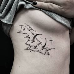 a woman's stomach with a cross and cloud tattoo on it