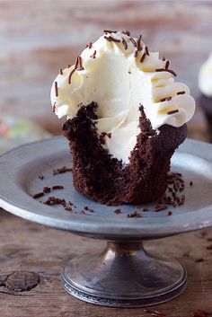 a chocolate cupcake with white frosting and sprinkles on a plate