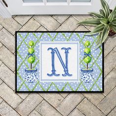 a door mat with the letter n and two potted plants in front of it