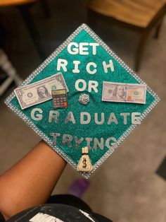 a green graduation cap that says get rich or graduate trying with money on top of it