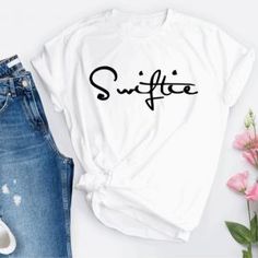 a white shirt with the word suitete on it next to jeans and pink flowers