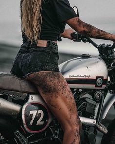 a woman sitting on top of a motorcycle with mud all over her legs and knees