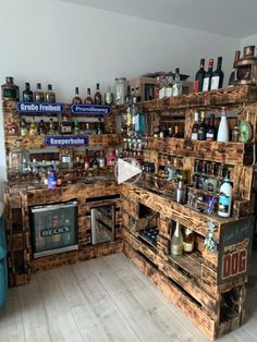 a kitchen with lots of wooden pallets on the wall and shelves filled with bottles