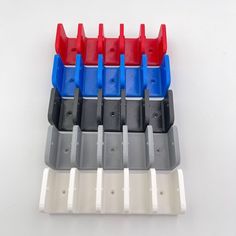 four rows of different colored plastic parts on a white surface with one red, one blue and one grey