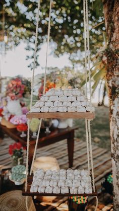 a wooden table topped with white cupcakes on top of a tree stump and hanging from strings