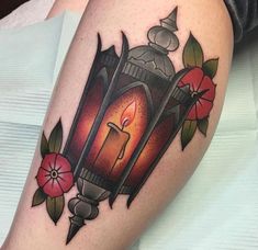 a tattoo with a lantern and flowers on the thigh, it looks like an old school tattoo