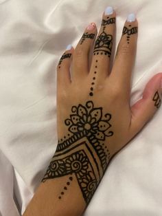 a woman's hand with henna tattoos on it