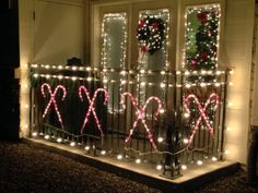 christmas lights on the balcony of a house decorated with wreaths and ribbons for holiday decorating