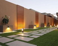 an outdoor area with grass and lights on the side of it, surrounded by stone walkways