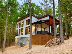 a house in the woods with lots of trees and logs stacked on top of it