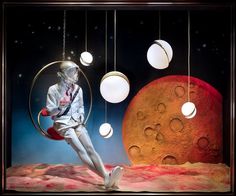 an astronaut is sitting on the moon in front of some balls and lights hanging from strings