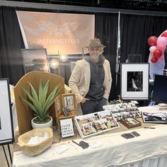 a man standing next to a table with pictures on it