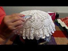 a person holding a pen near a white doily on a table