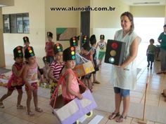 a woman standing in front of a group of children wearing paper hats and holding signs