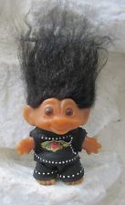 an orange troll doll with black hair on it's head standing in the snow